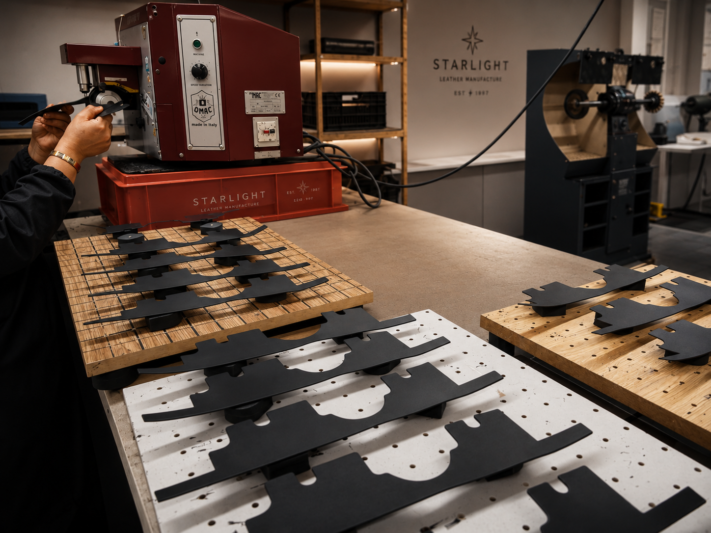 Pièces cuir noir en série dans l'atelier Starlight, machine OMAC et logo manufacture